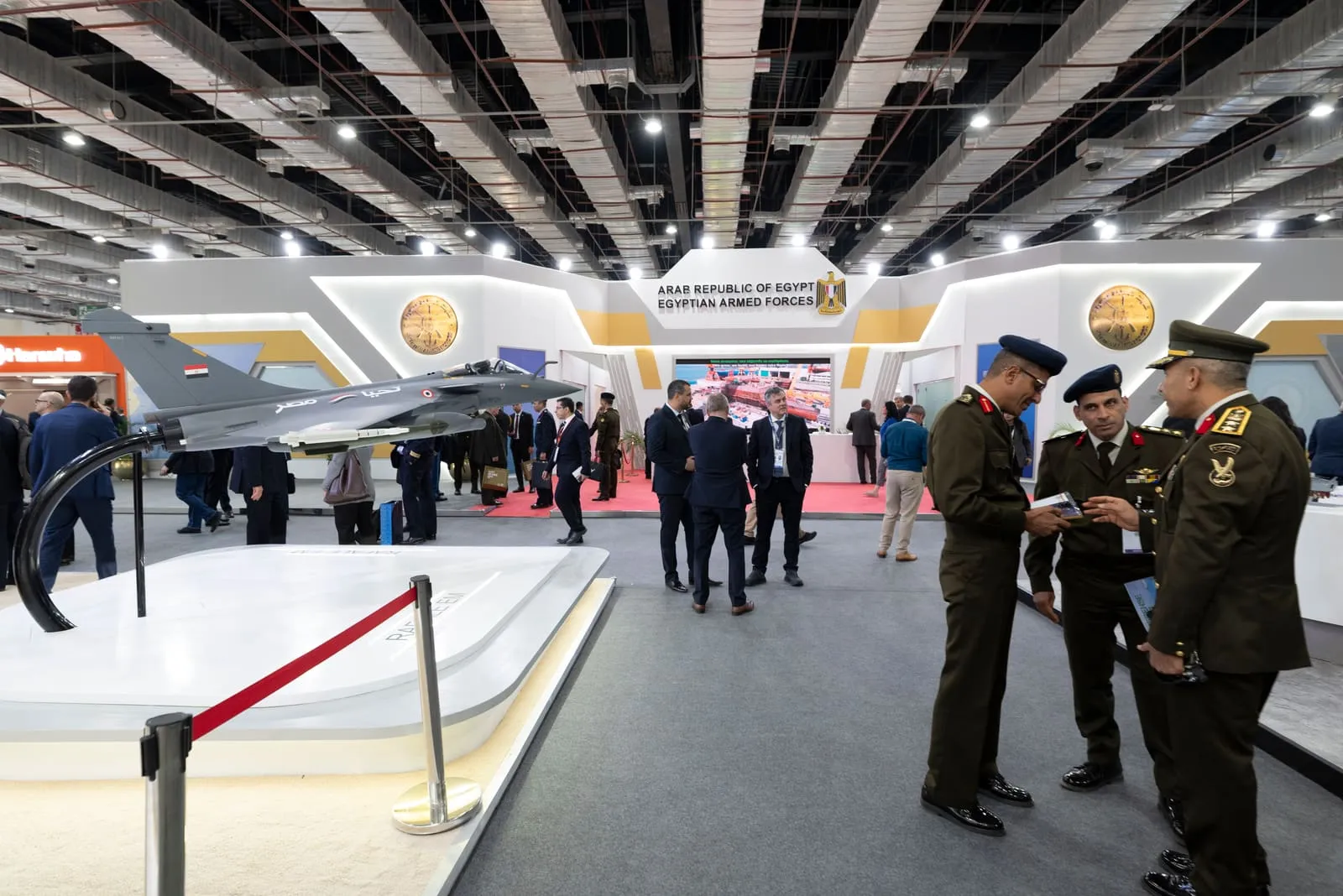 Military officers reviewing an exhibition stand beside a national pavilion