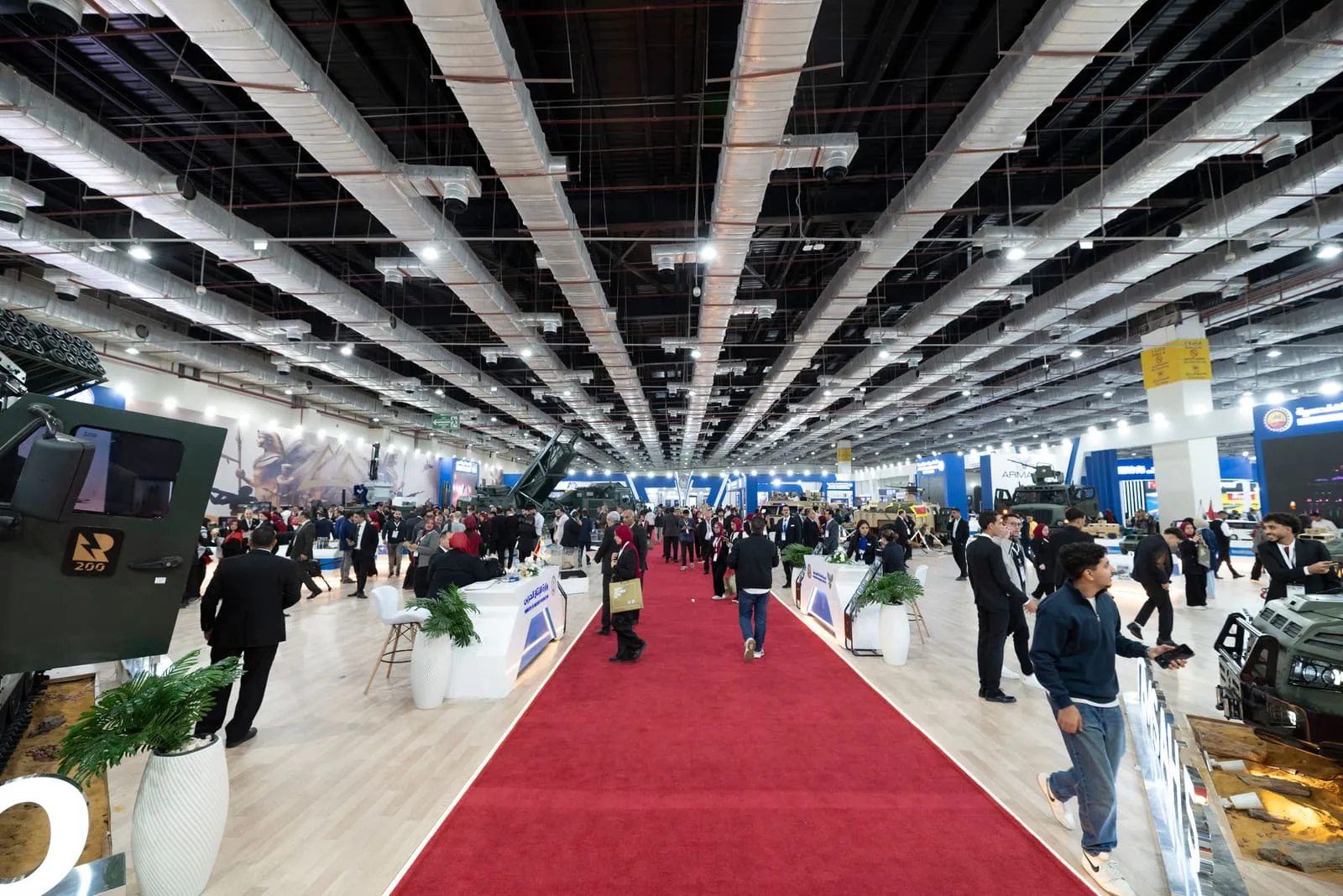 Red-carpet aisle through a crowded exhibition hall